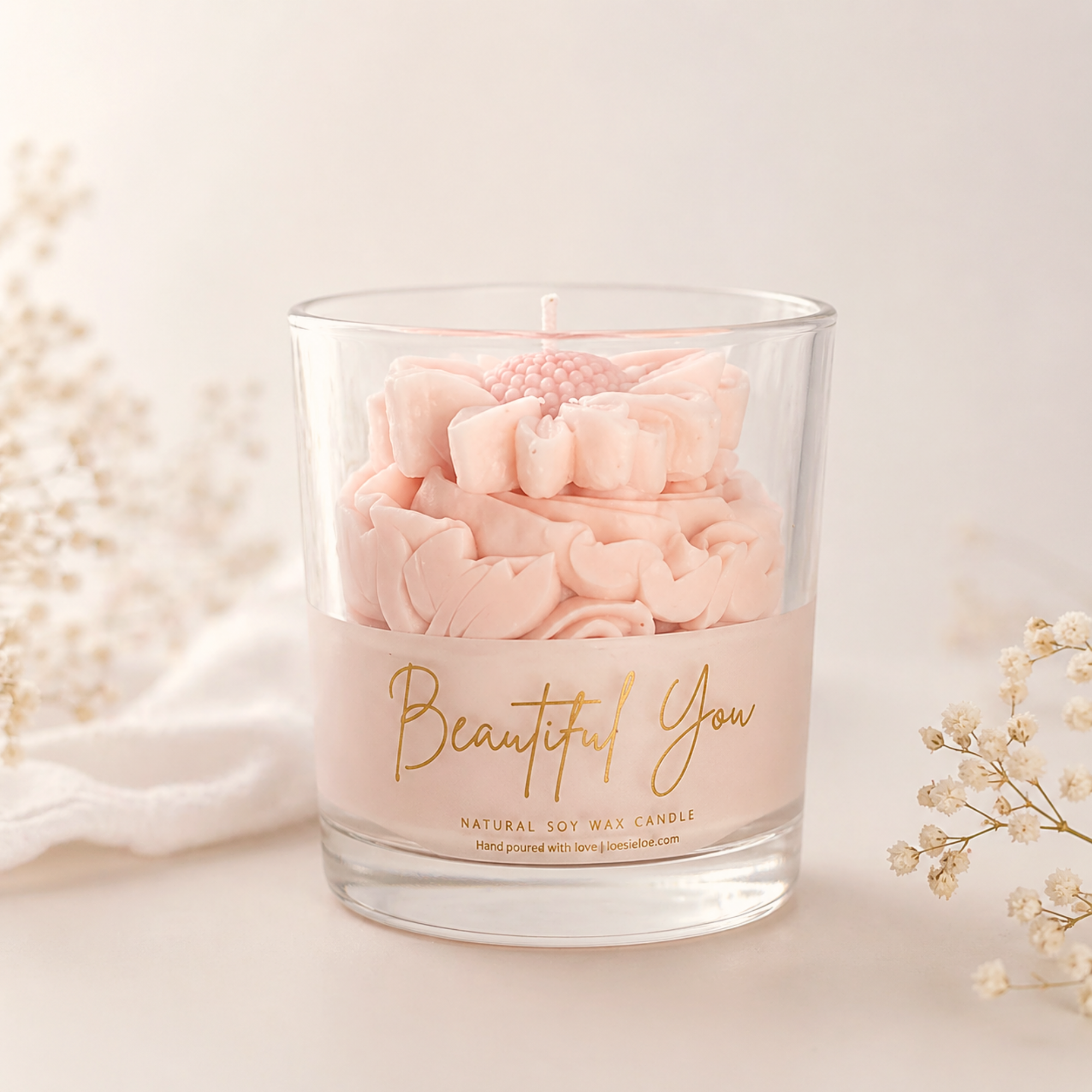 Beautiful You scented candle in soft pink with golden lettering, graceful whipped top and daisy on top.

