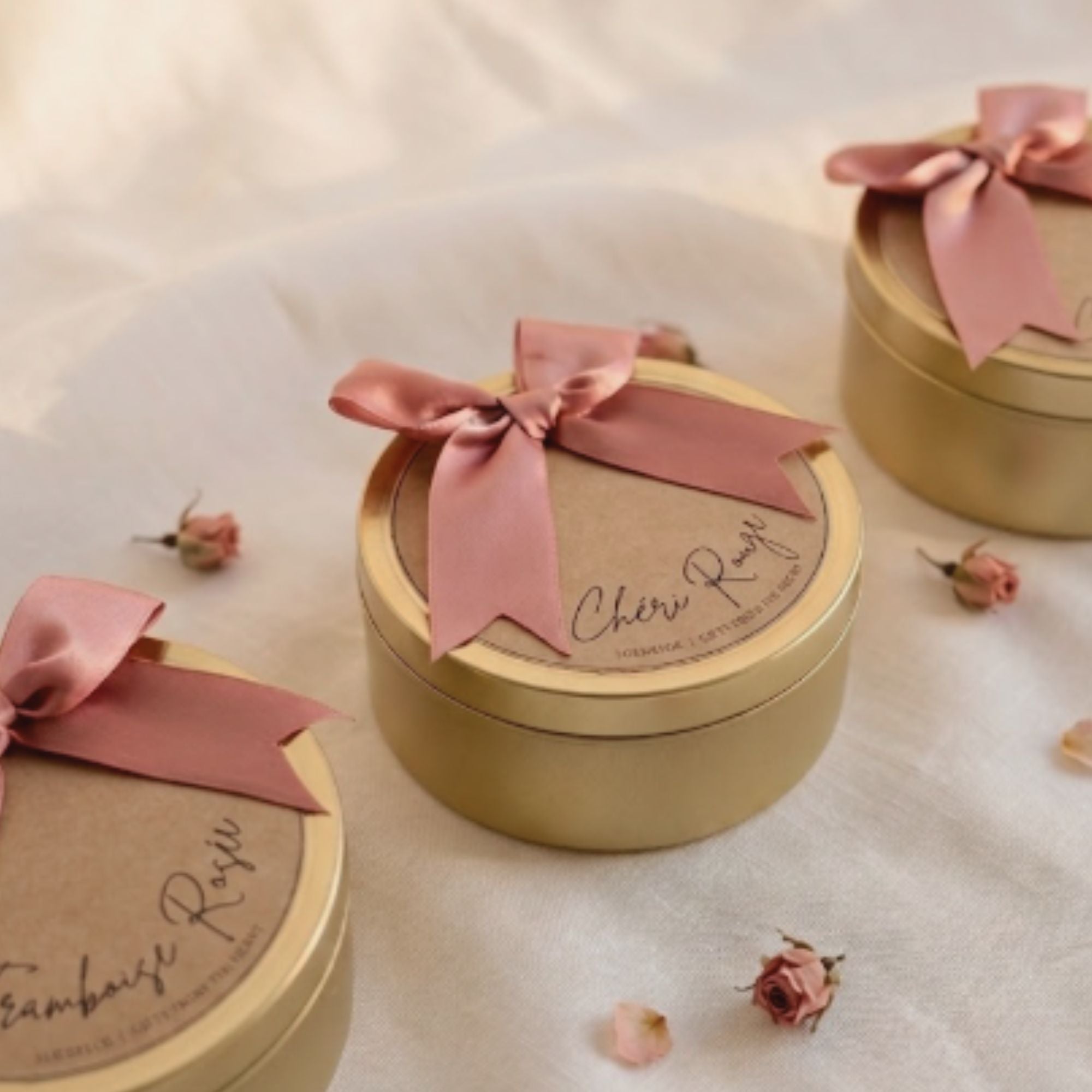La Vie en Rose Golden Floral Candle made from natural soy wax in a golden candle tin with a soft pink bow and soft floral scent. La Vie en Rose Golden Floral Candle van natuurlijke sojawas in gouden candle tin met roze strik en zachte bloemige geur.